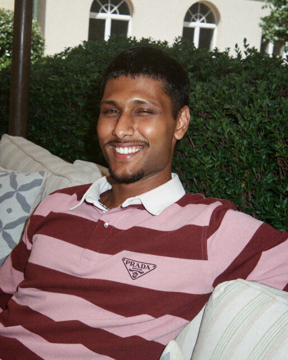 Shaq, co-founder, portrait on a garden sofa, smiling in a striped rugby shirt