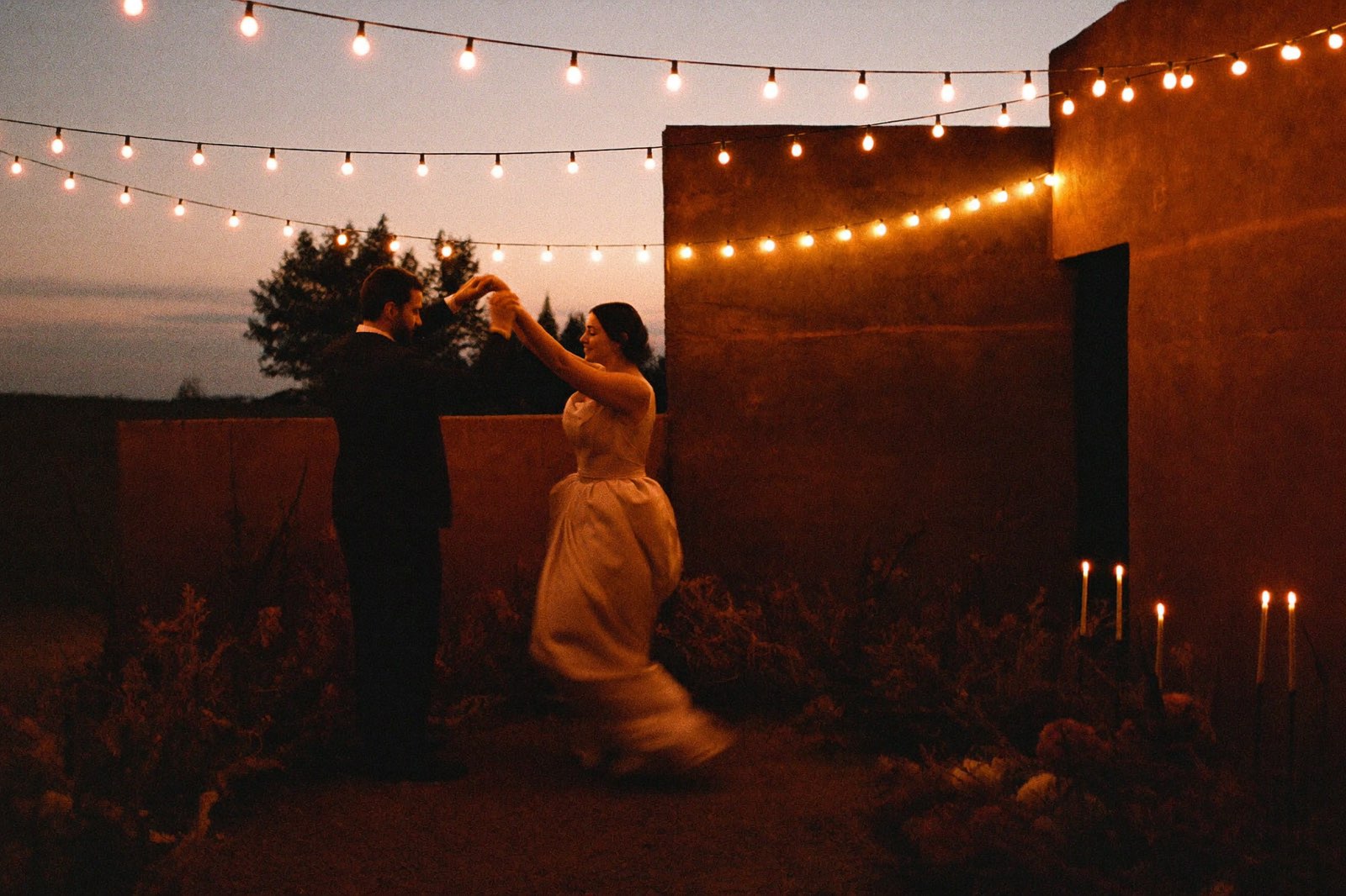 Rushmi To My Vows, a couple dancing at dusk under strings of festoon lights
